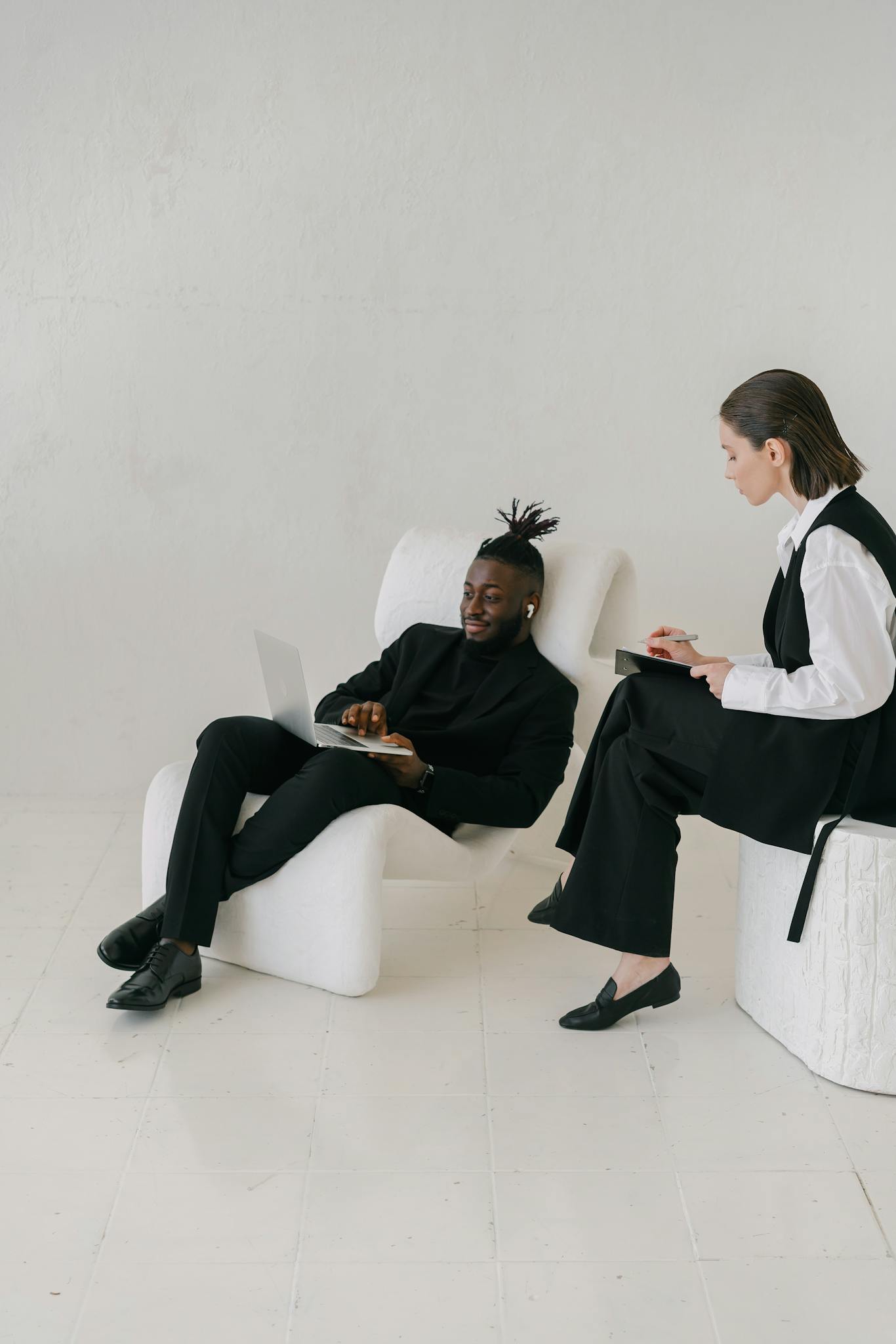 Two professionals discuss business strategy in a minimalist office setting.